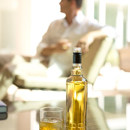 Spirit bottle with screw cap on table with man in background